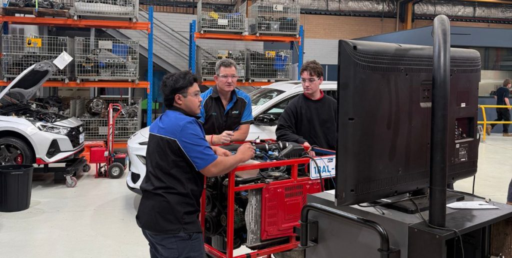 "MTA WA trainer Justin teaching automotive students hands-on air conditioning diagnostics on an engine test rig in the workshop